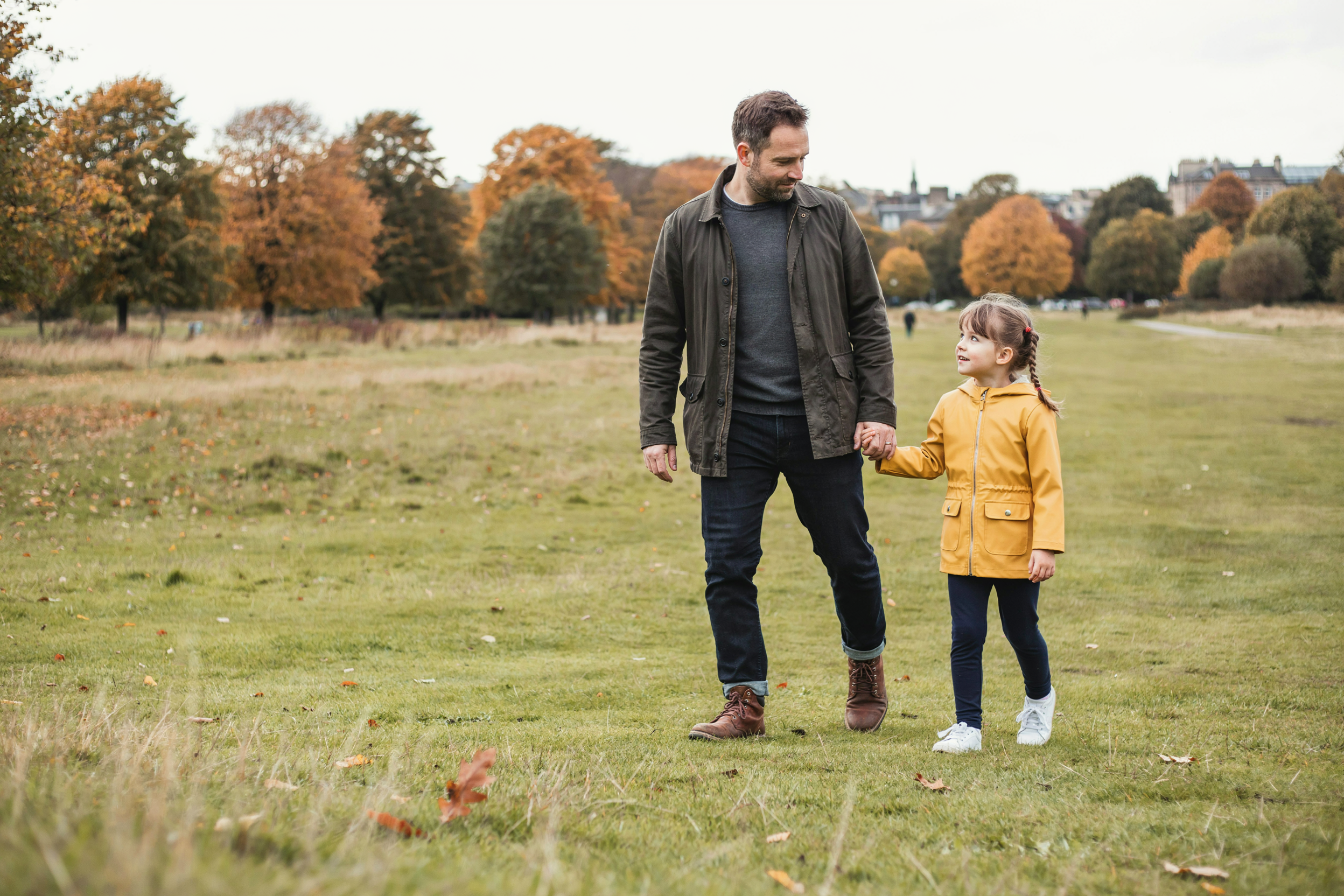 Mature student walking across Leith Links in Edinburgh with his young daughter