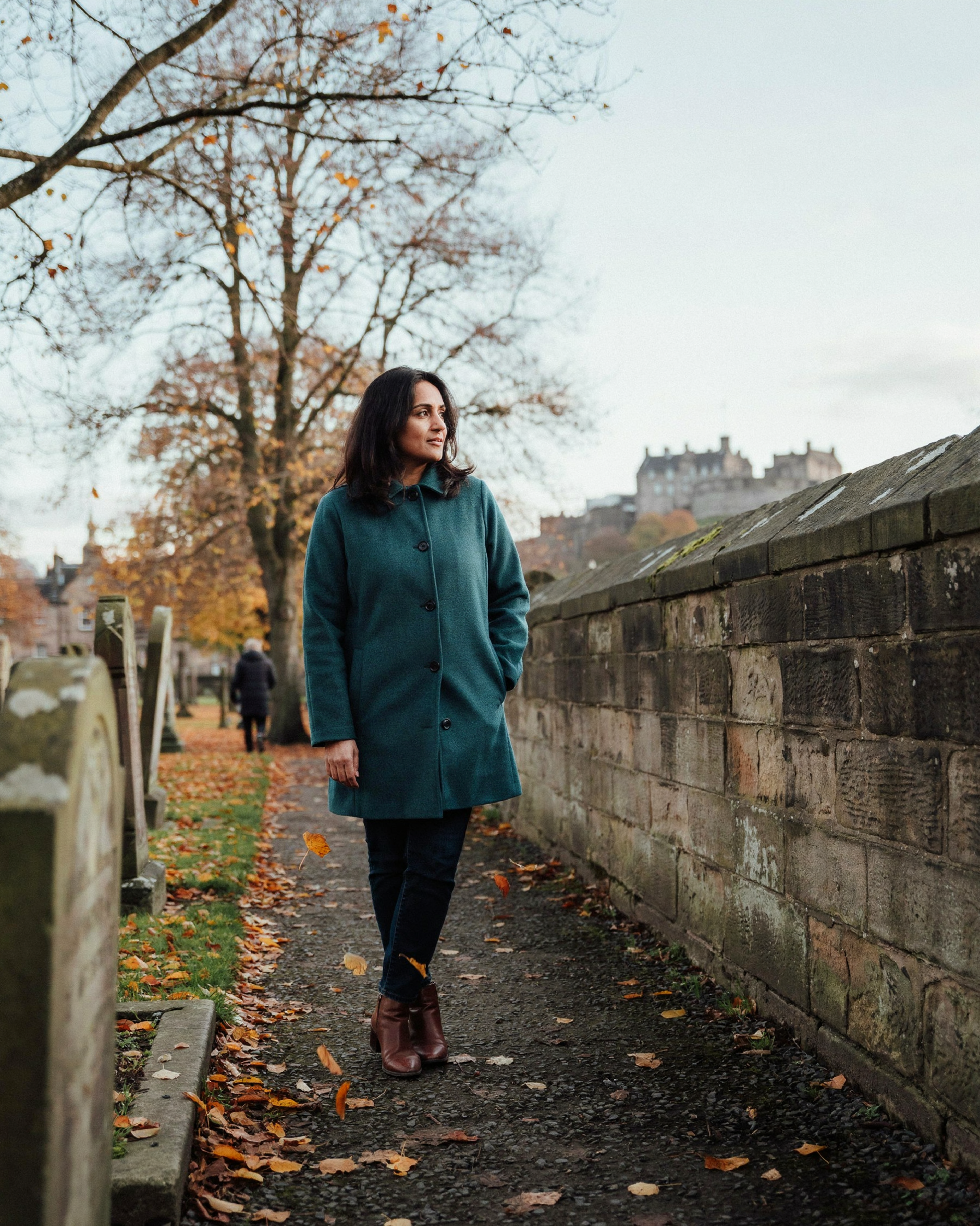 Woman walking through Greyfriars Kirkyard in Edinburgh on an autumn morning, close to Forrest Pharmacy