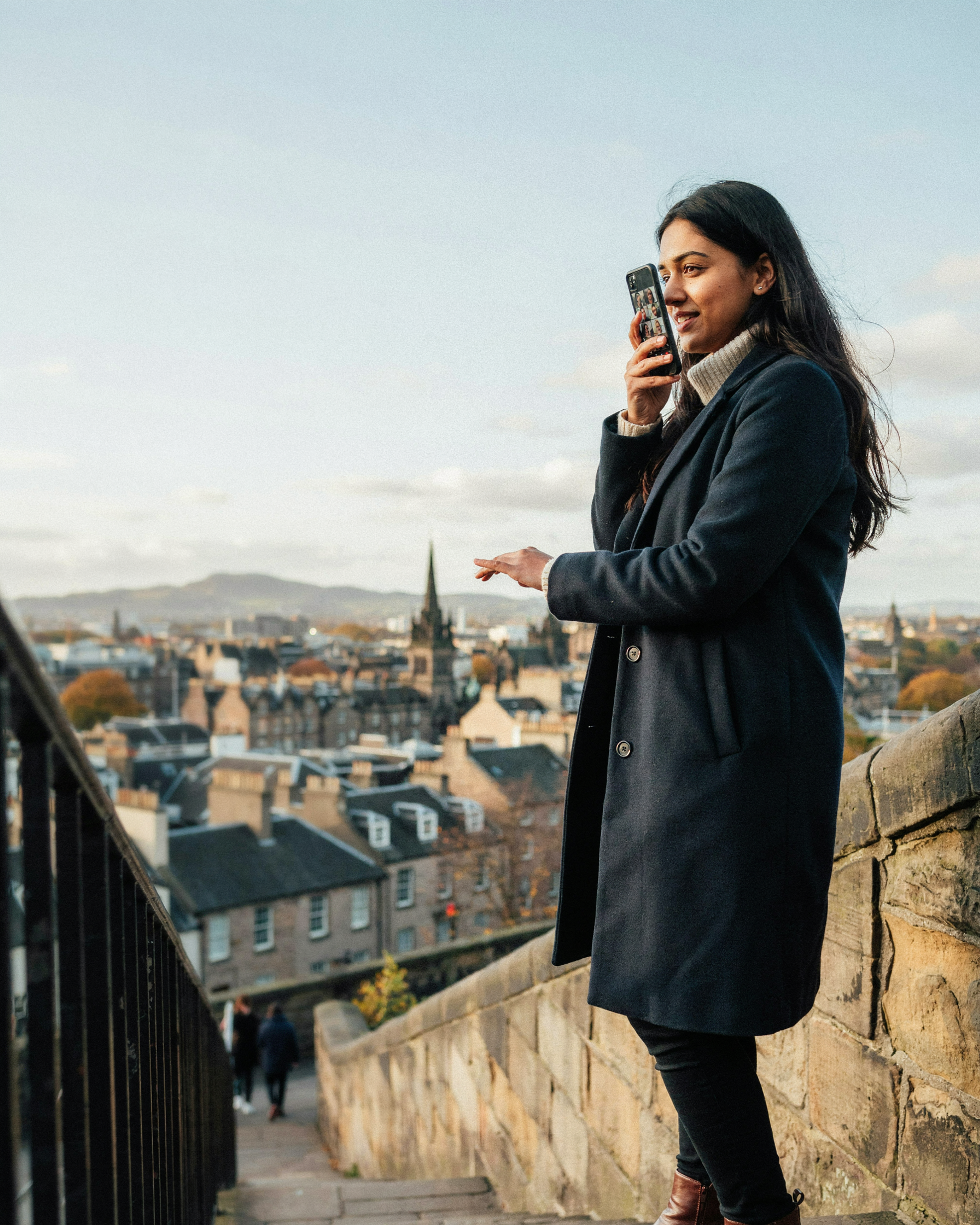 International student on a video call home from Castlehill in Edinburgh with the city view behind
