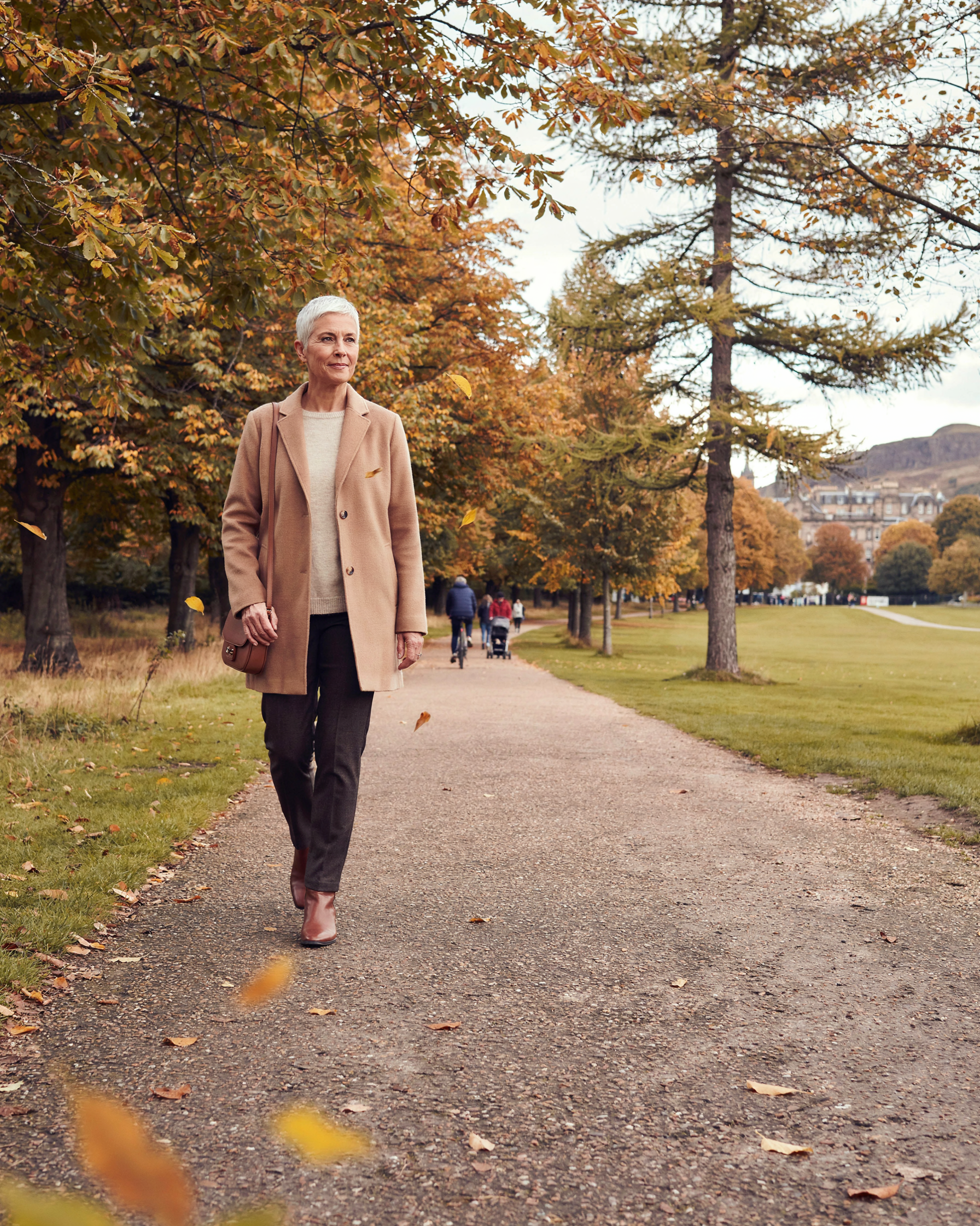 Woman walking along Middle Meadow Walk in Edinburgh among autumn trees