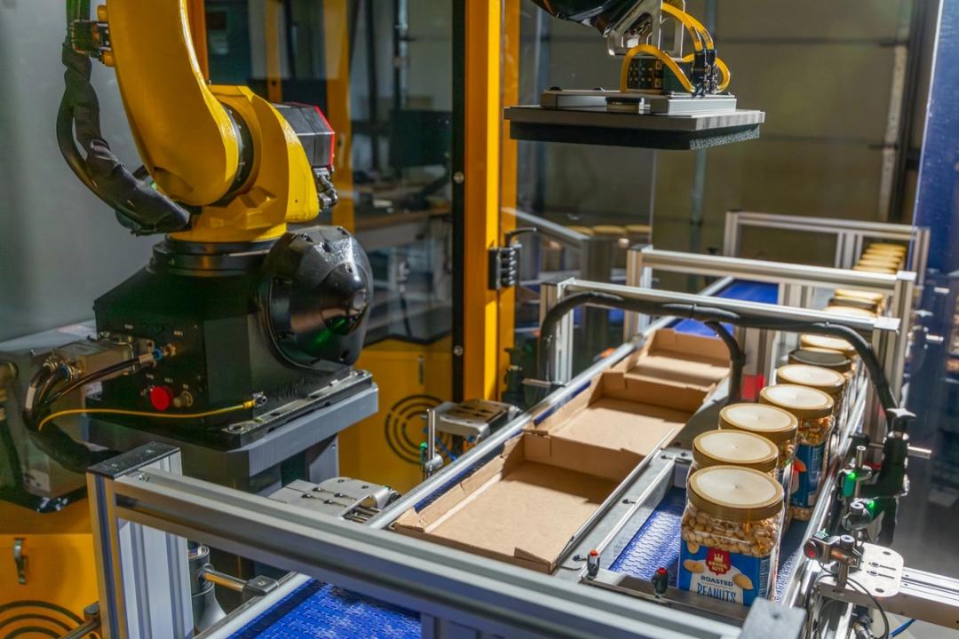 Robotic vacuum gripper lifting jars of peanuts during automated end-of-line case packing