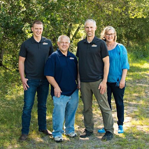 The Resch Enterprises team: Zach Dean, Greg Resch, Andy Resch, and Becky Resch-Dean standing outdoors