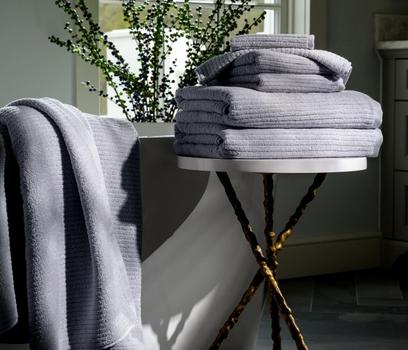 Pebble Plush Performance Towels next to a bath tub