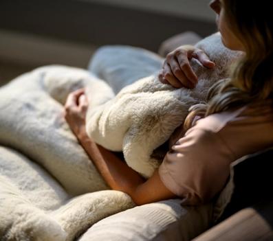 Woman snuggling in chair with Faux Fur Blanket in color Almond