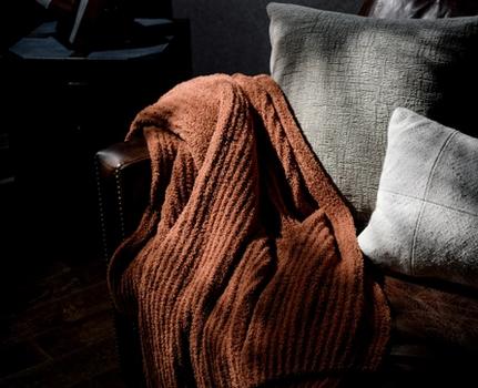Clay super cozy throw blanket laying on the side of a couch, perfect for decor