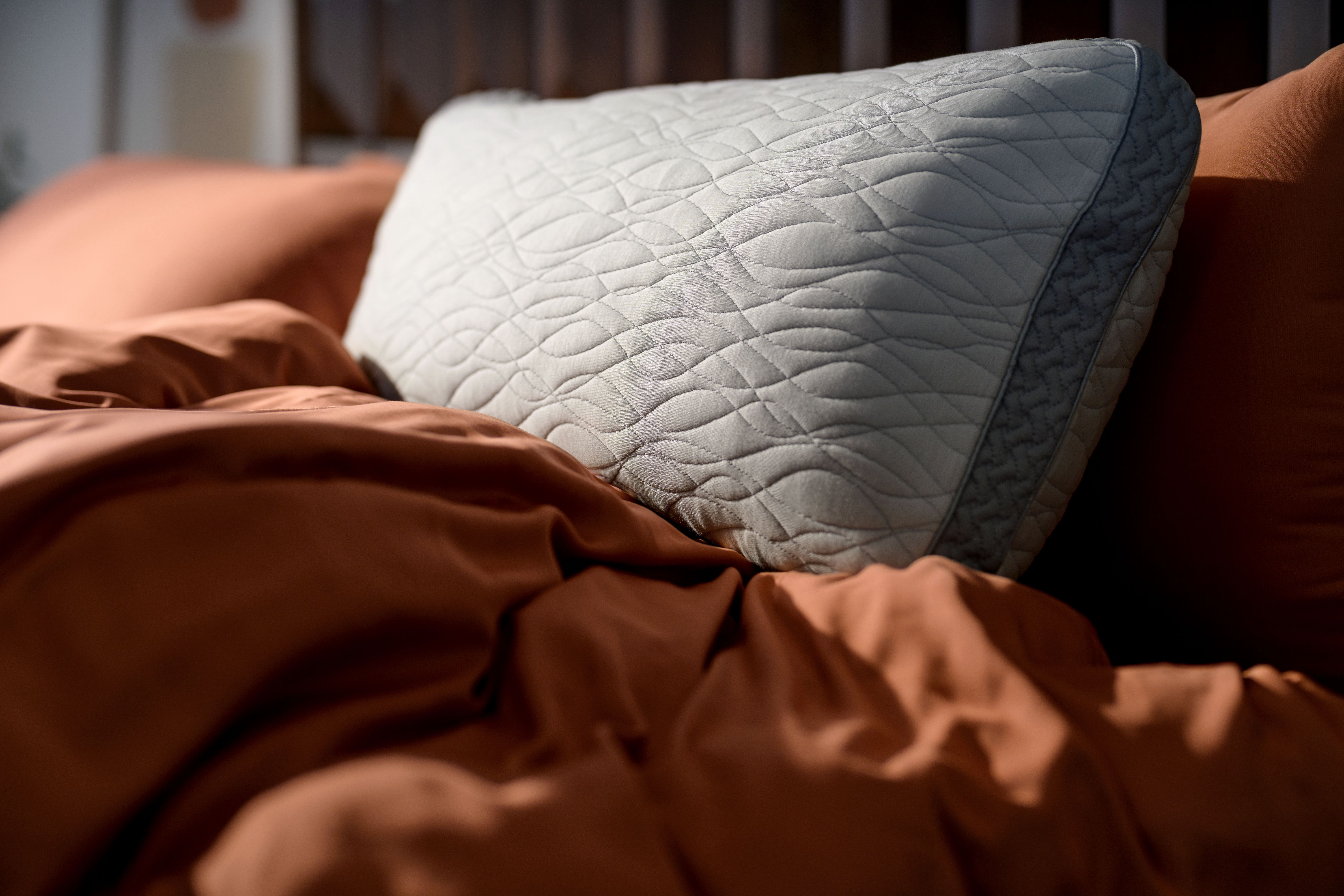 Dual Chamber Pillow resting on a bed with terracotta