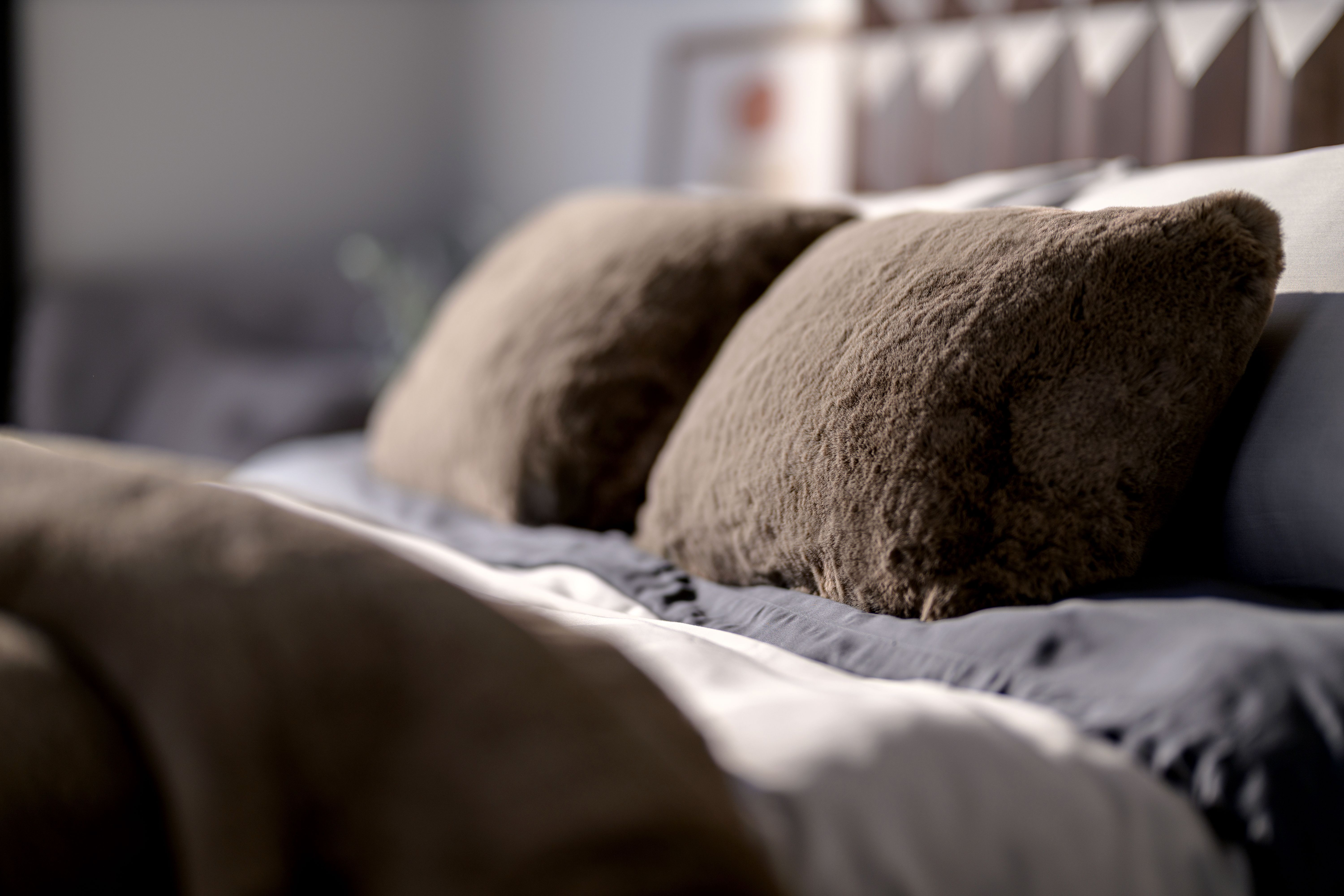 Truffle Faux fur Pillow sitting on bed