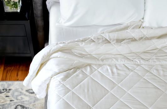 Ivory bamboo blanket tucked on bed