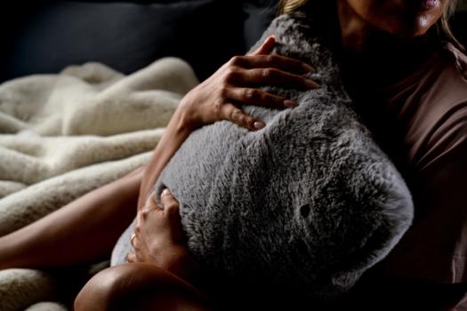 Woman hugging a cozy & luxurious throw pillow with a faux fur cover in fog