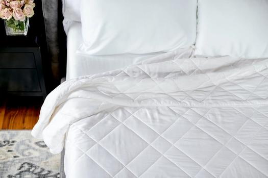 White bamboo blanket tucked on bed