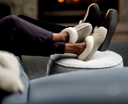 Woman and Man lounging wearing Signature Slippers in Birch & Walnut