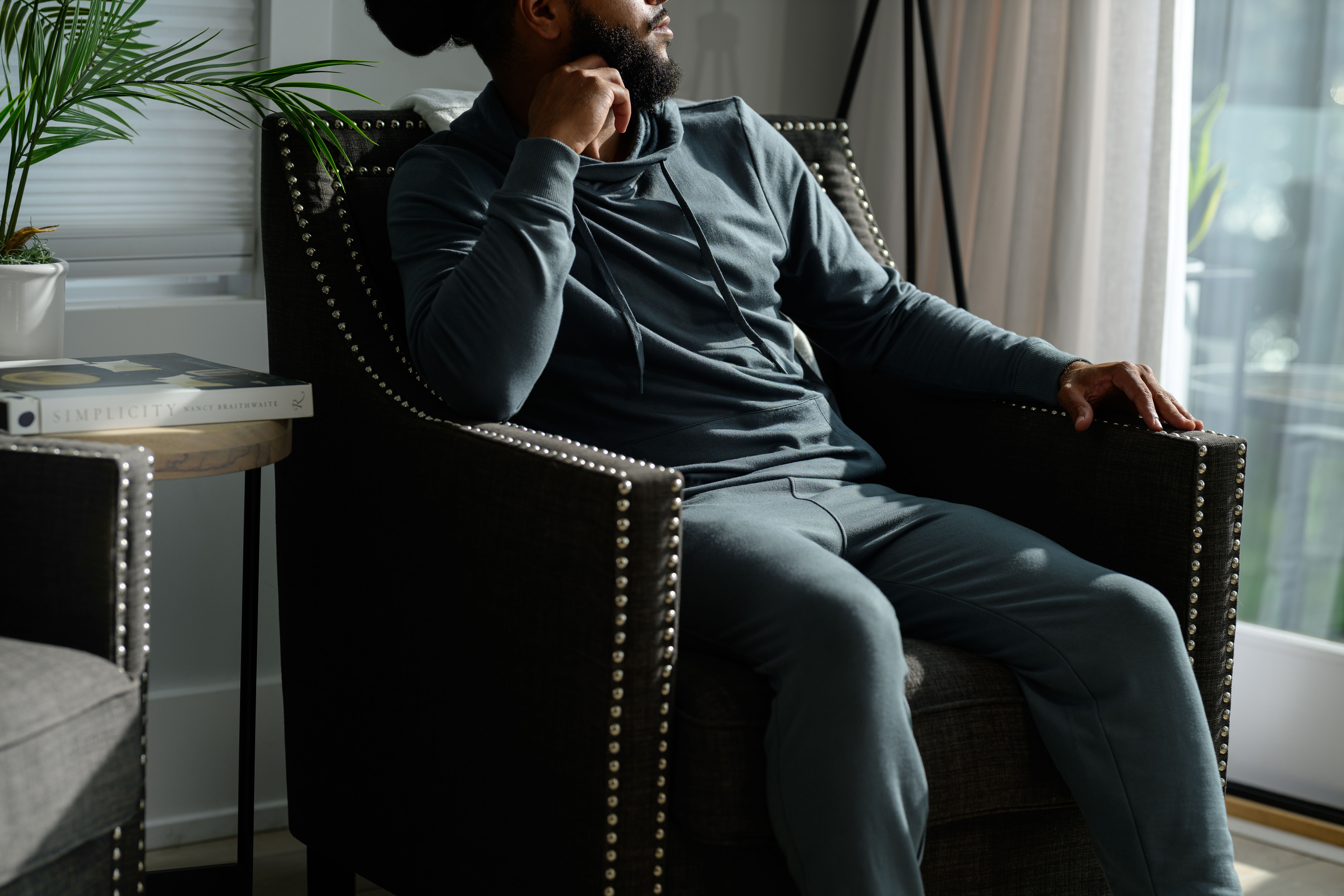Man lounging in the cozy Spruce Essential Hoodie
