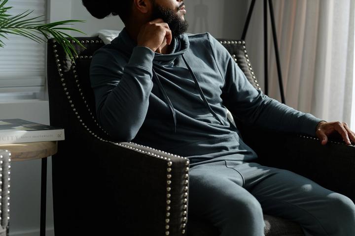 Man lounging in the cozy Spruce Essential Hoodie
