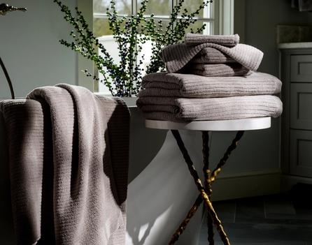 Oyster Plush Performance Towels next to a bath tub