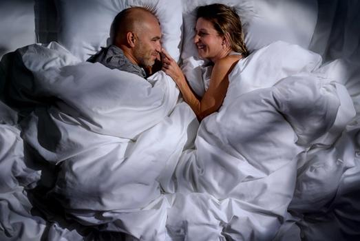 Couple in bed sleeping under a cozy, fluffy comforter