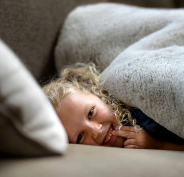 Child under faux fur blanket, focusing on the cruelty free
