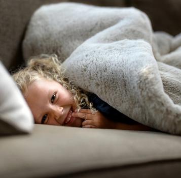 Child under faux fur blanket, focusing on the cruelty free