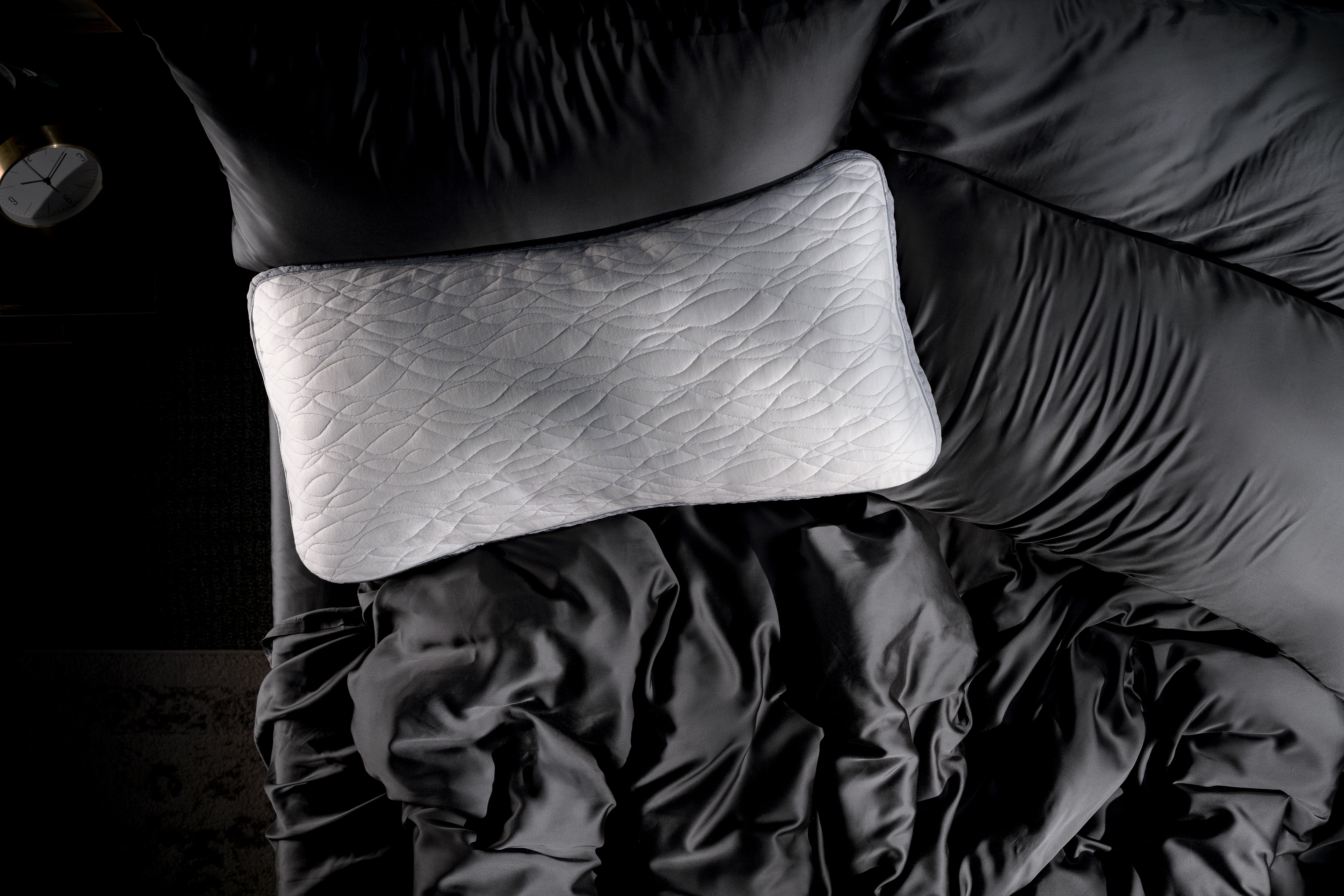 Dual Chamber Pillow laying on bed with charcoal sheets