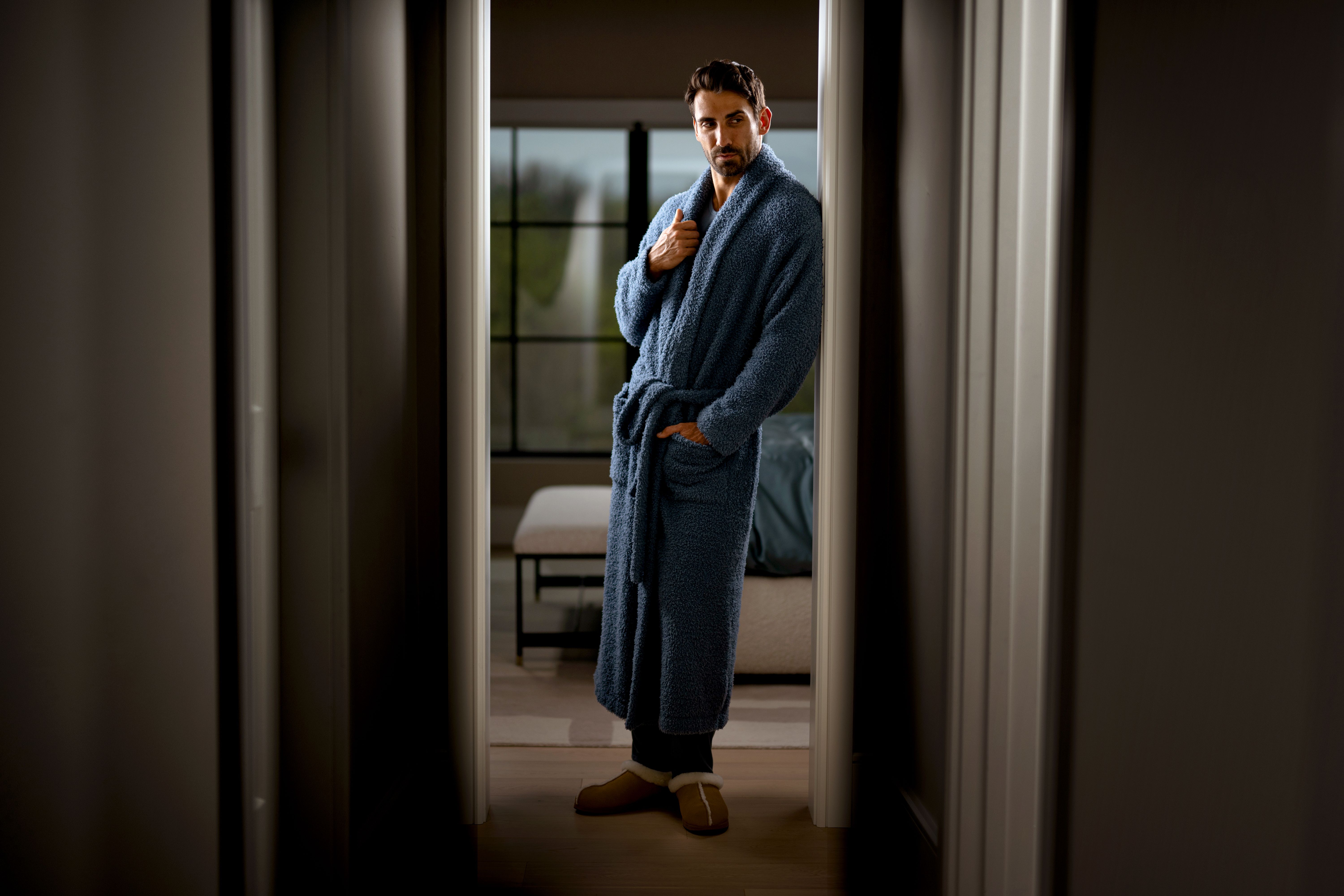 Man standing in hallway, loving his Drift Ultra Plush Robe