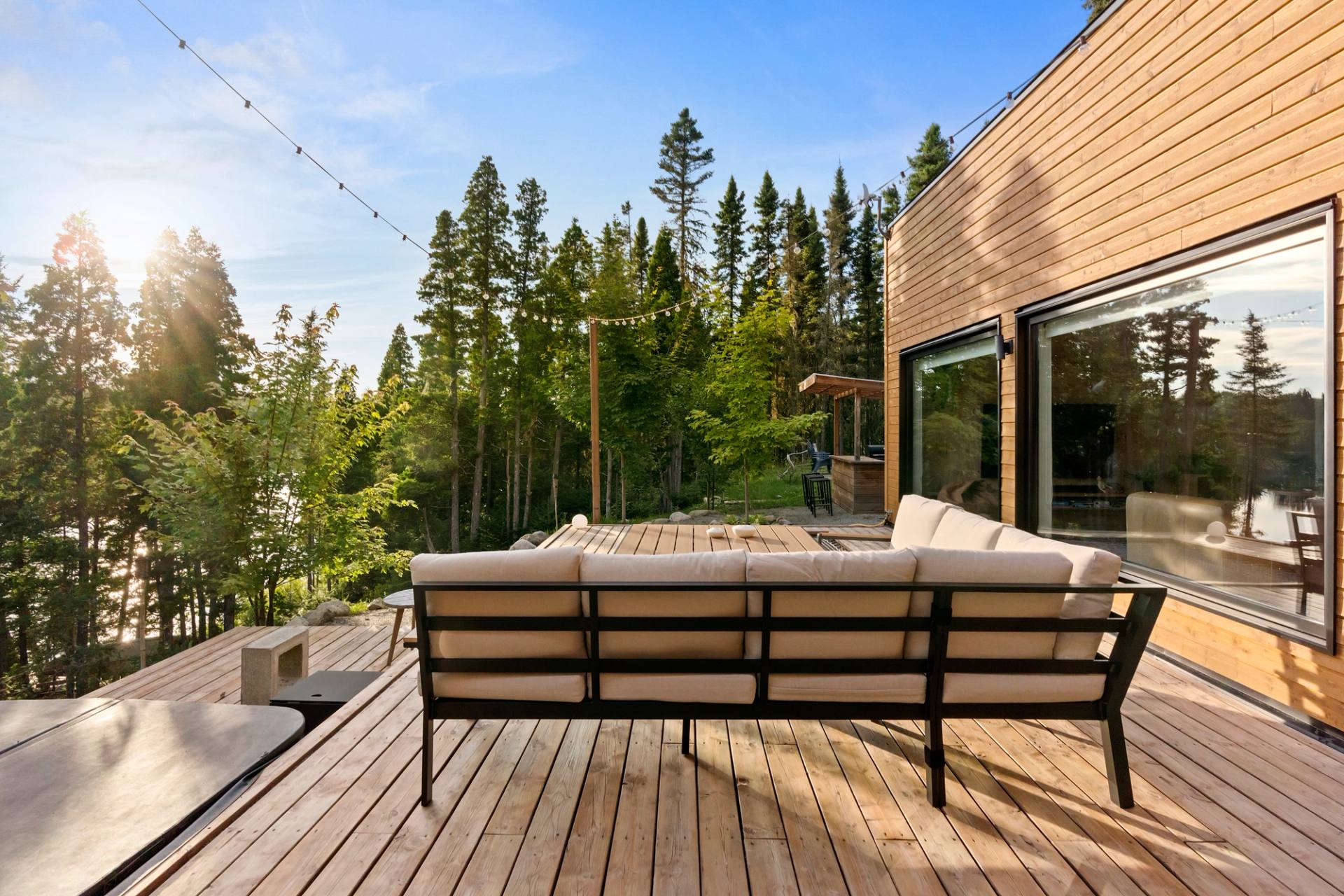 Terrasse du chalet avec canape d'exterieur, entouree de coniferes