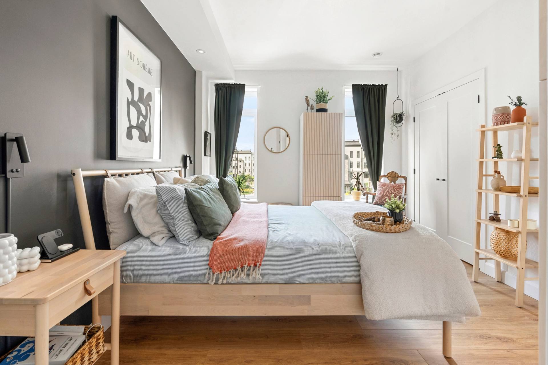 Chambre principale avec lit habillé de coussins, mur d'accent gris foncé et rideaux verts