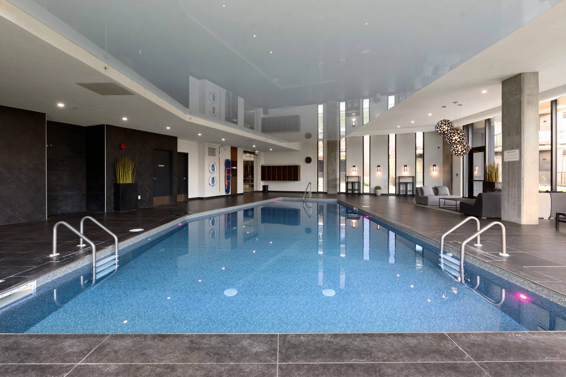 Piscine intérieure d’un immeuble, murs sombres et eau bleu grisâtre