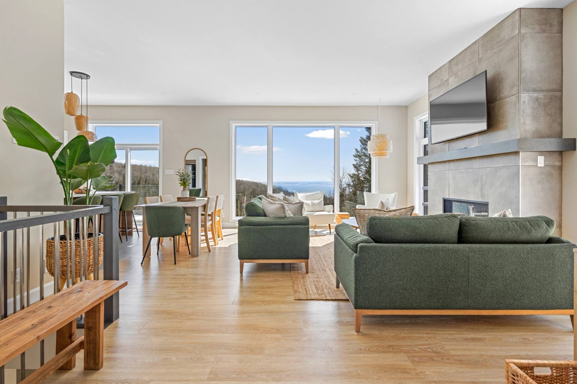 Sejour avec canape vert et grandes fenetres ouvertes sur le paysage