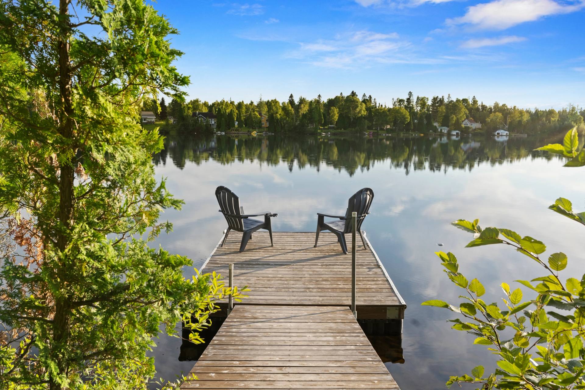 Quai sur le lac avec deux chaises Adirondack face a la foret, au calme