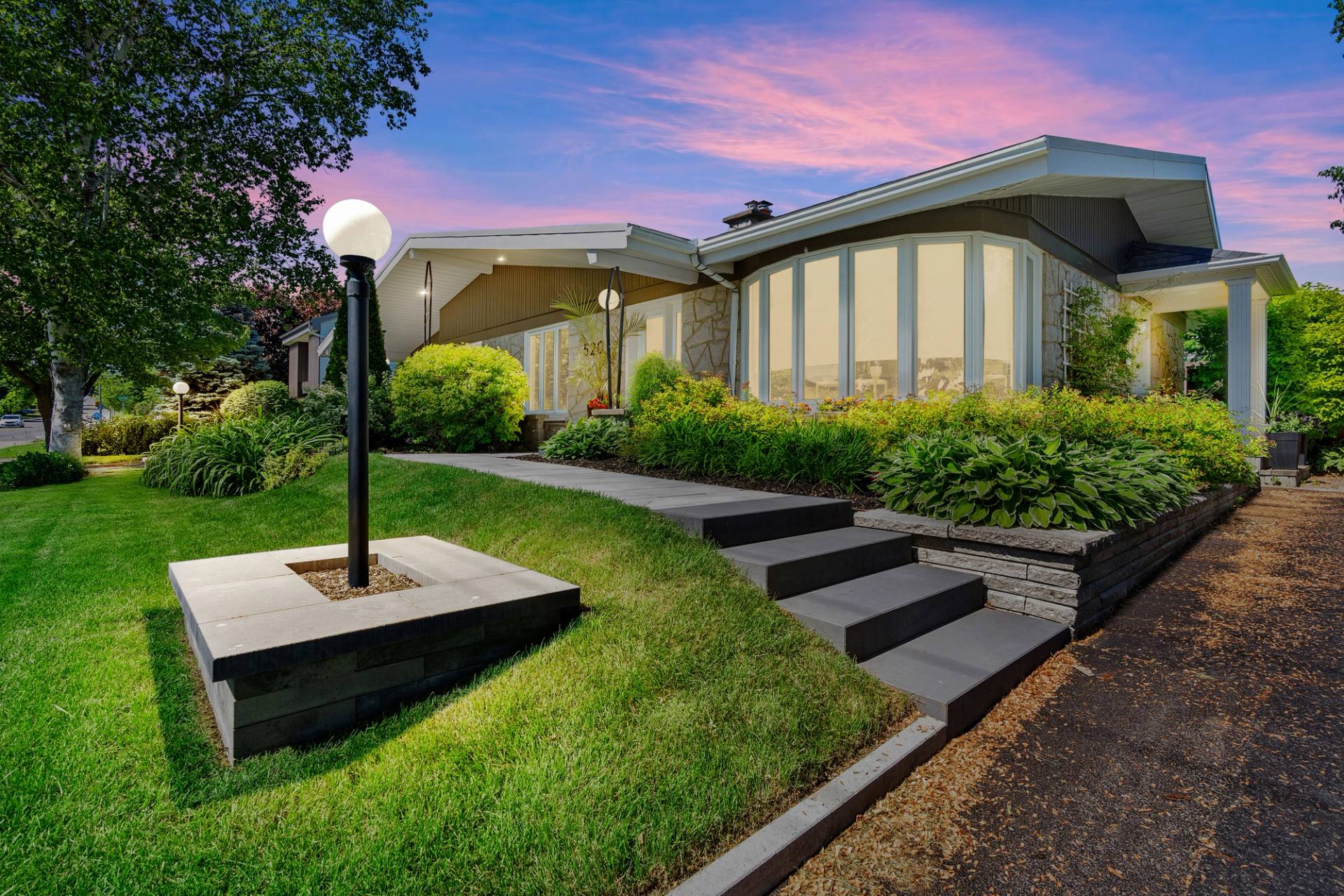Maison d'architecte aux grandes baies vitrées, terrain paysager en paliers et lampadaire de jardin