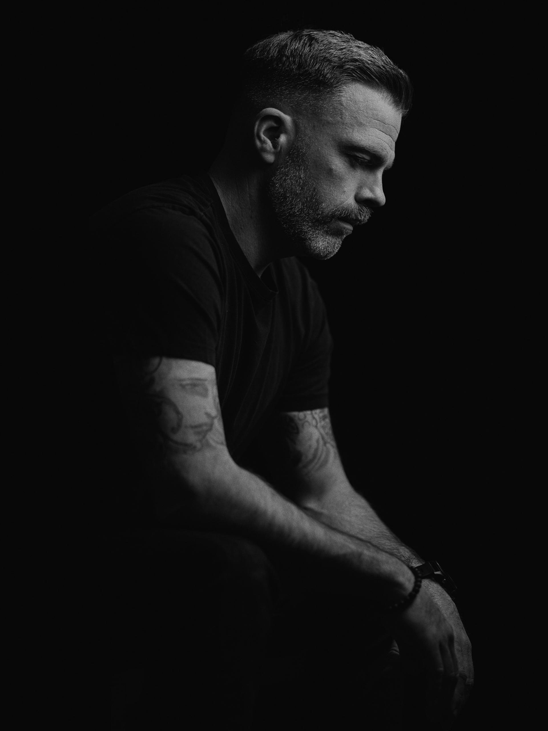 Portrait masculin en noir et blanc sur fond sombre, eclairage contraste