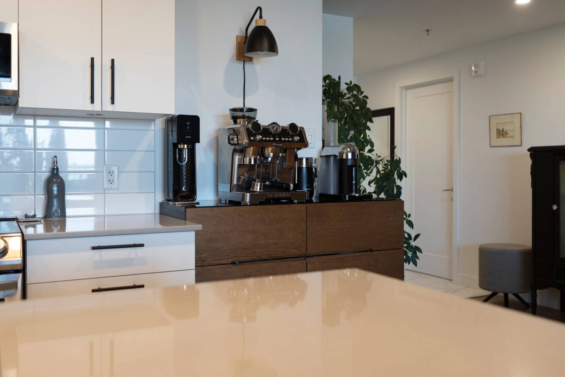Coin café d’une cuisine avec machine espresso sur un meuble de bois, sous une lumière jaune