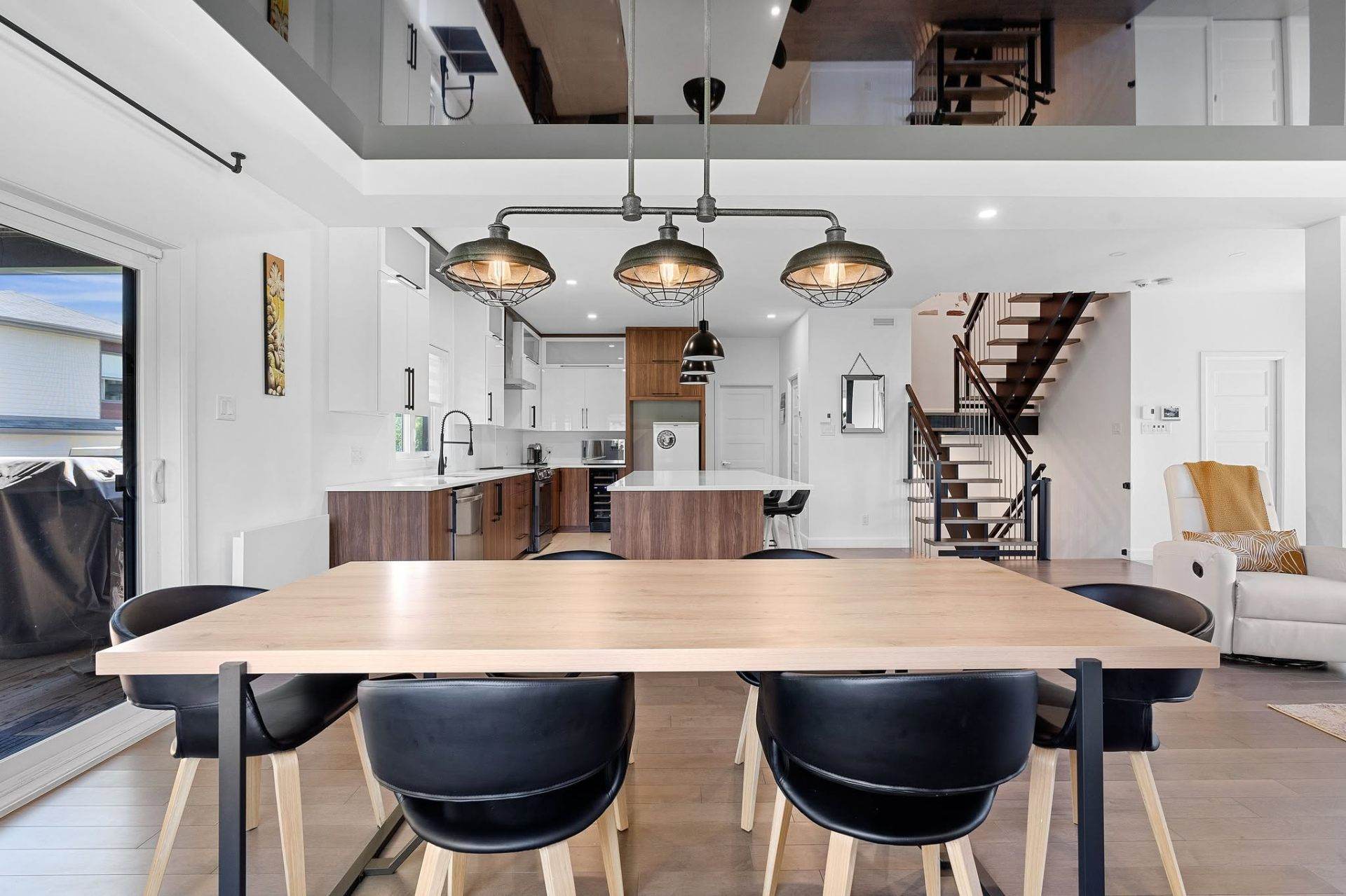 Aire ouverte avec cuisine, salle à manger et escalier suspendu vers une mezzanine