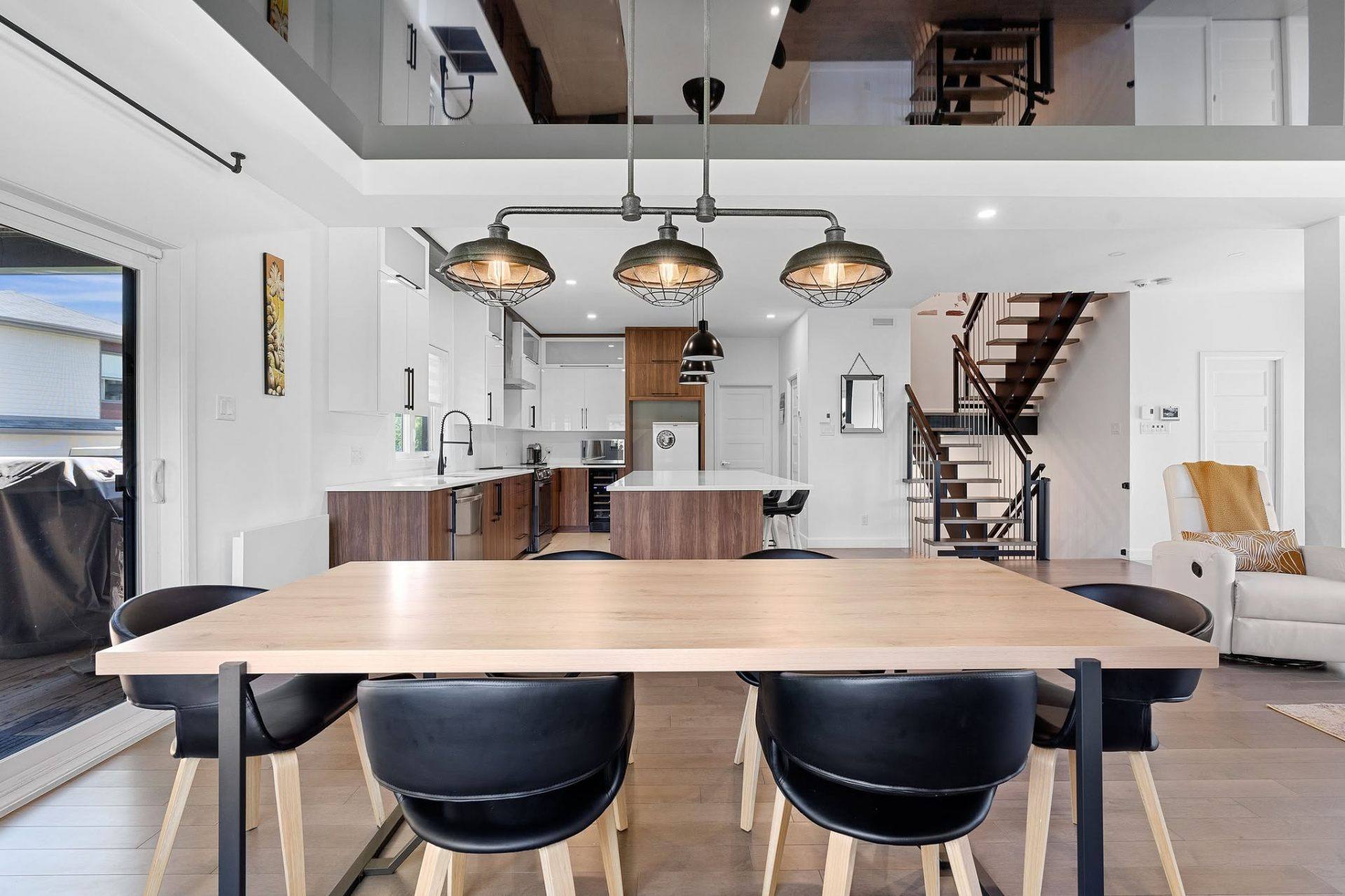 Aire ouverte avec cuisine, salle à manger et escalier suspendu vers une mezzanine