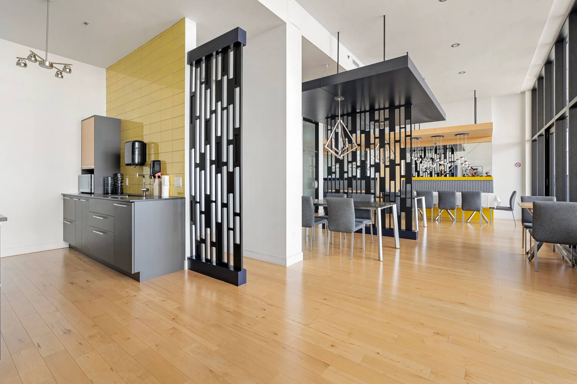 Aire commune d'un immeuble avec cuisinette, plancher de bois clair et cloison ajourée