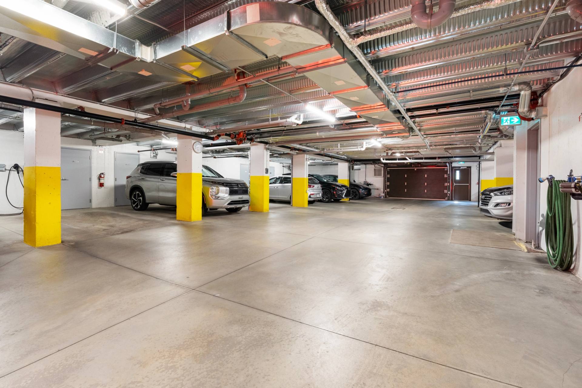 Stationnement intérieur d'un immeuble, colonnes jaunes et plafond industriel apparent