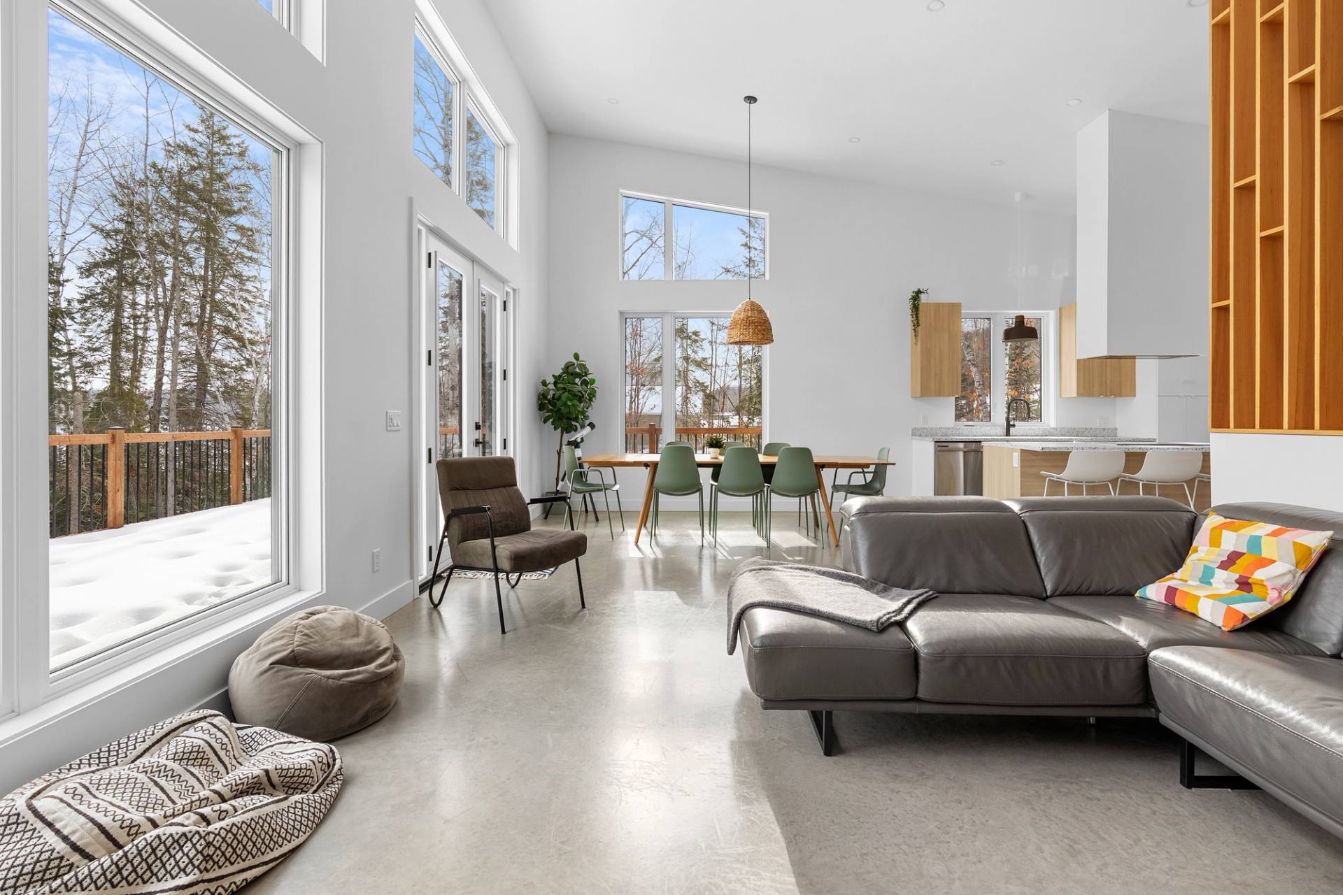 Sejour lumineux au plafond haut, canape gris et grandes baies vitrees