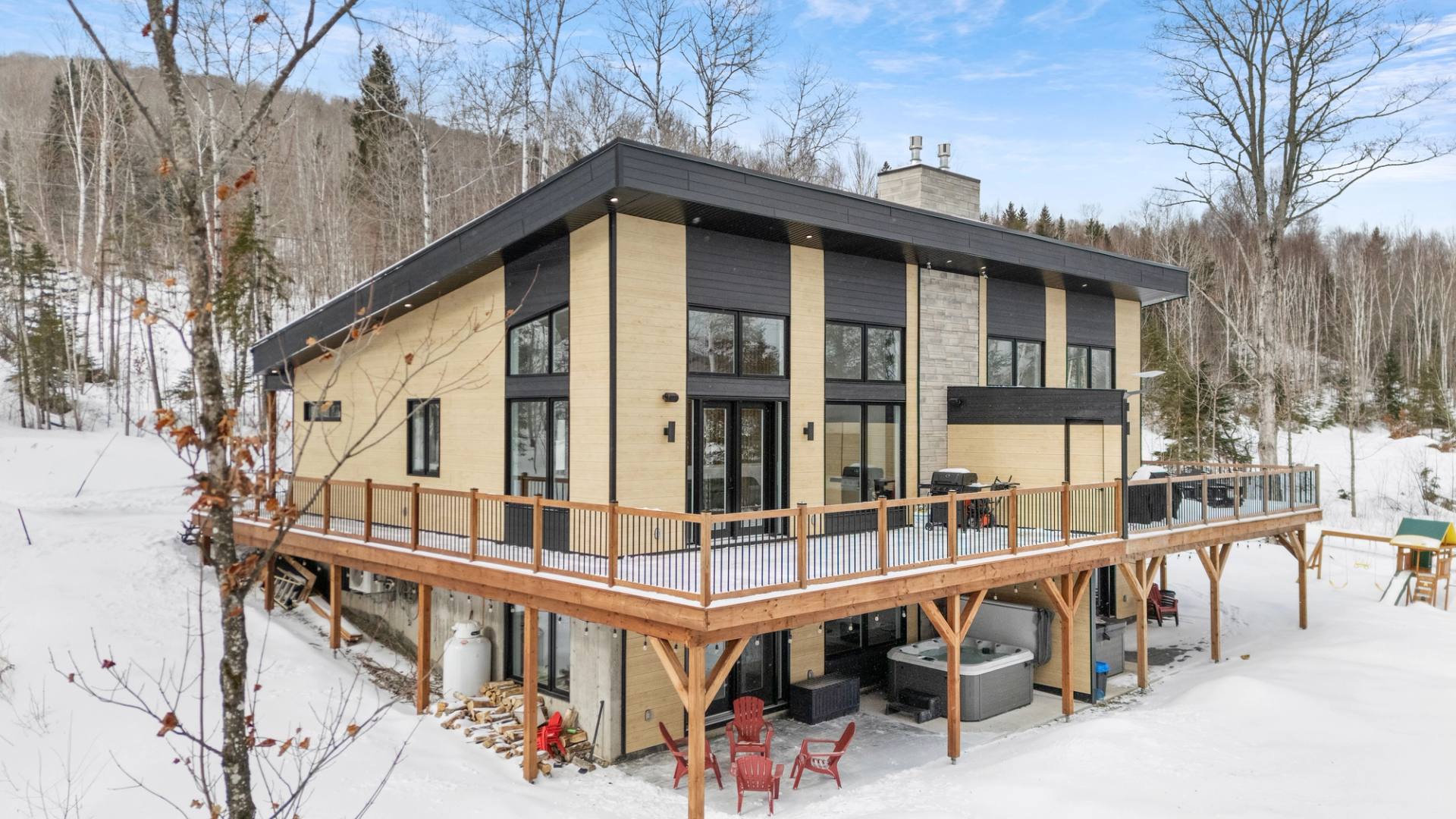 Facade contemporaine en bois et noir avec terrasse, sous la neige