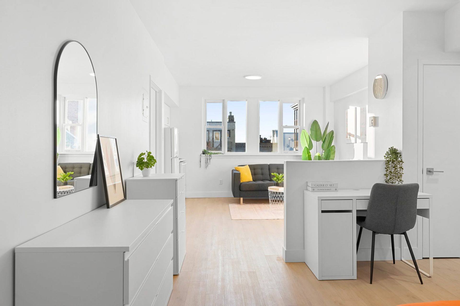 Studio blanc lumineux avec miroir en arche, coin bureau et vue sur les toits de Québec