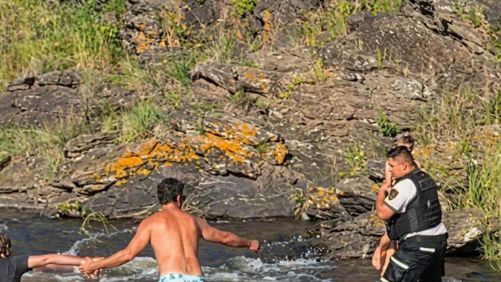 Agente de la Policía rescata a niño atrapado por la corriente de un río