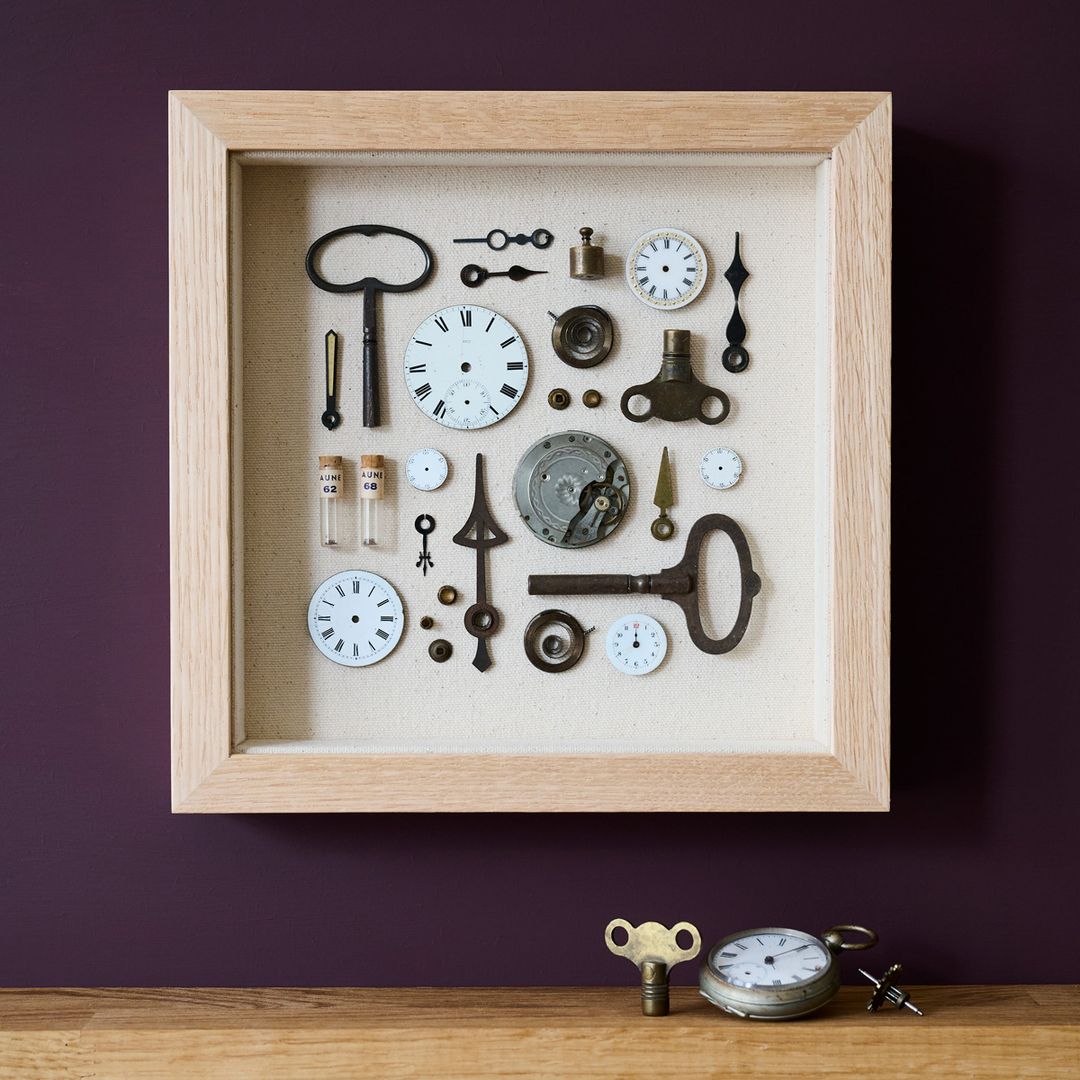A piece of assemblage art made up from lots of vintage watch faces and clock parts on a canvas background, framed in Oak