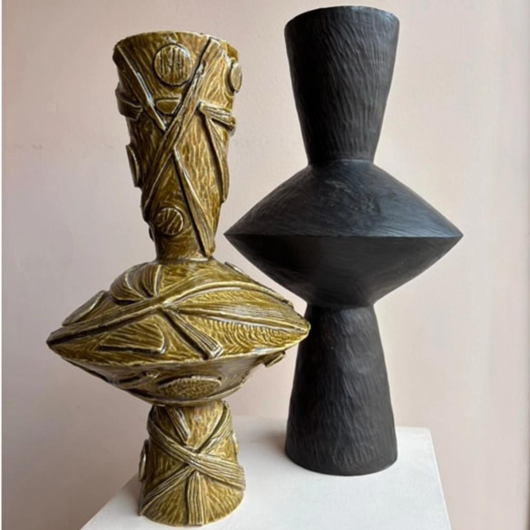 Two ceramic angular vases. The left is heavily textured and glazed in a honey coloured glaze and the right is smooth and glazed in satin black.