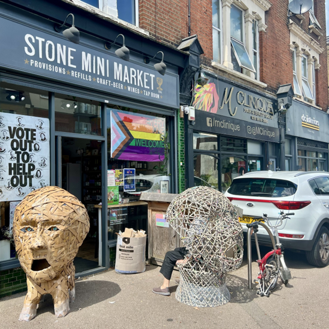 Two cyclists outside the Stone Mini Mart, an Arts Trail must-see, who are getting ready for a fun ride but wear raincoats just in case!