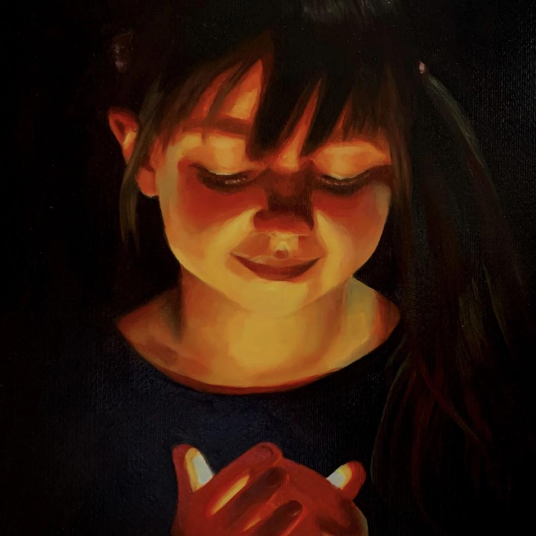 Young girl holding a light source, reflecting a vibrant warmth onto her skin.