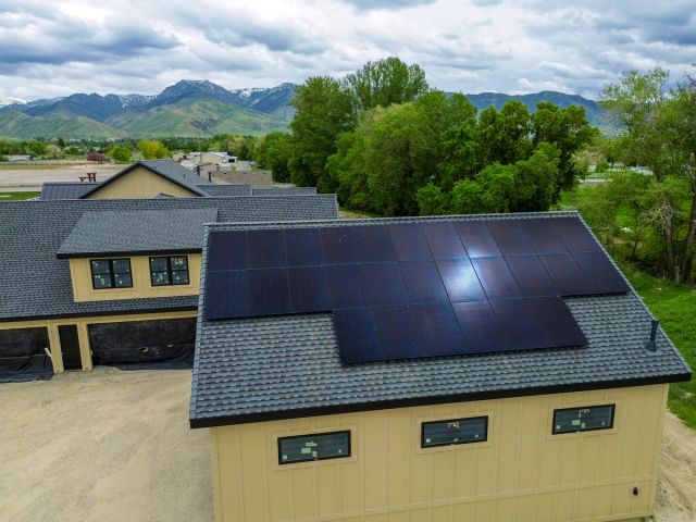 All-black rooftop solar array on a two-story home below the mountains