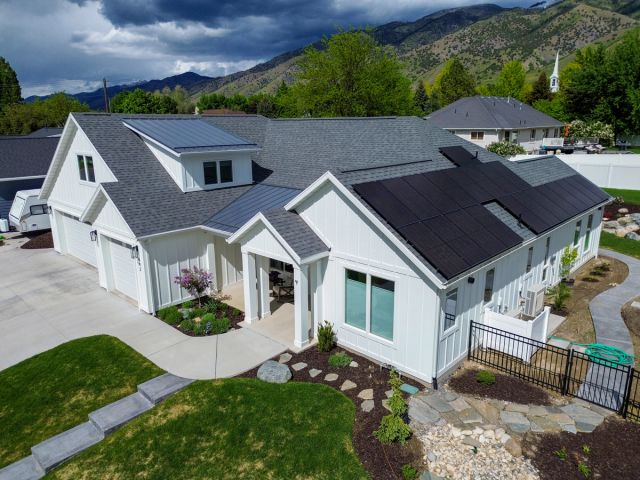 White farmhouse-style home with an all-black rooftop solar array