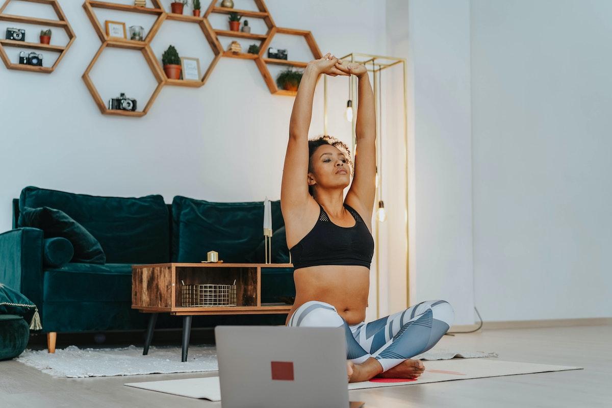A women taking a live online yoga class from her living room.