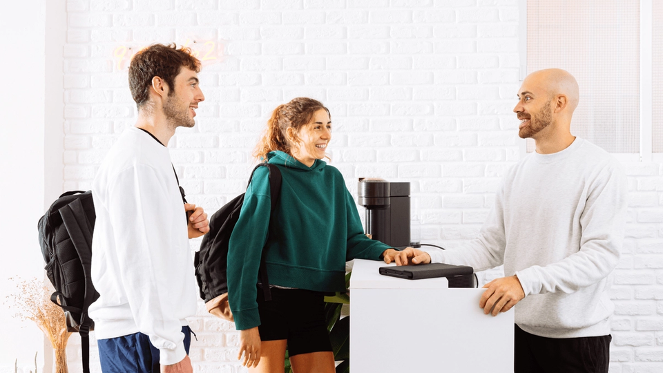 Two guests making a direct booking at a hotel reception counter.