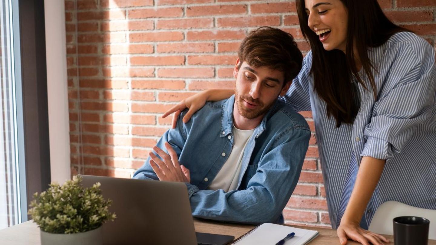 A couple improving their hotel SEO on a laptop.