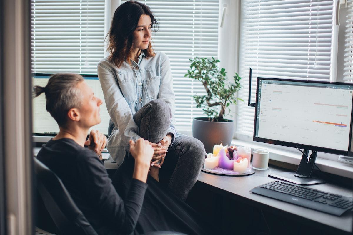 A man and a women sitting a desk looking at a computer monitor showing a Google calendar.