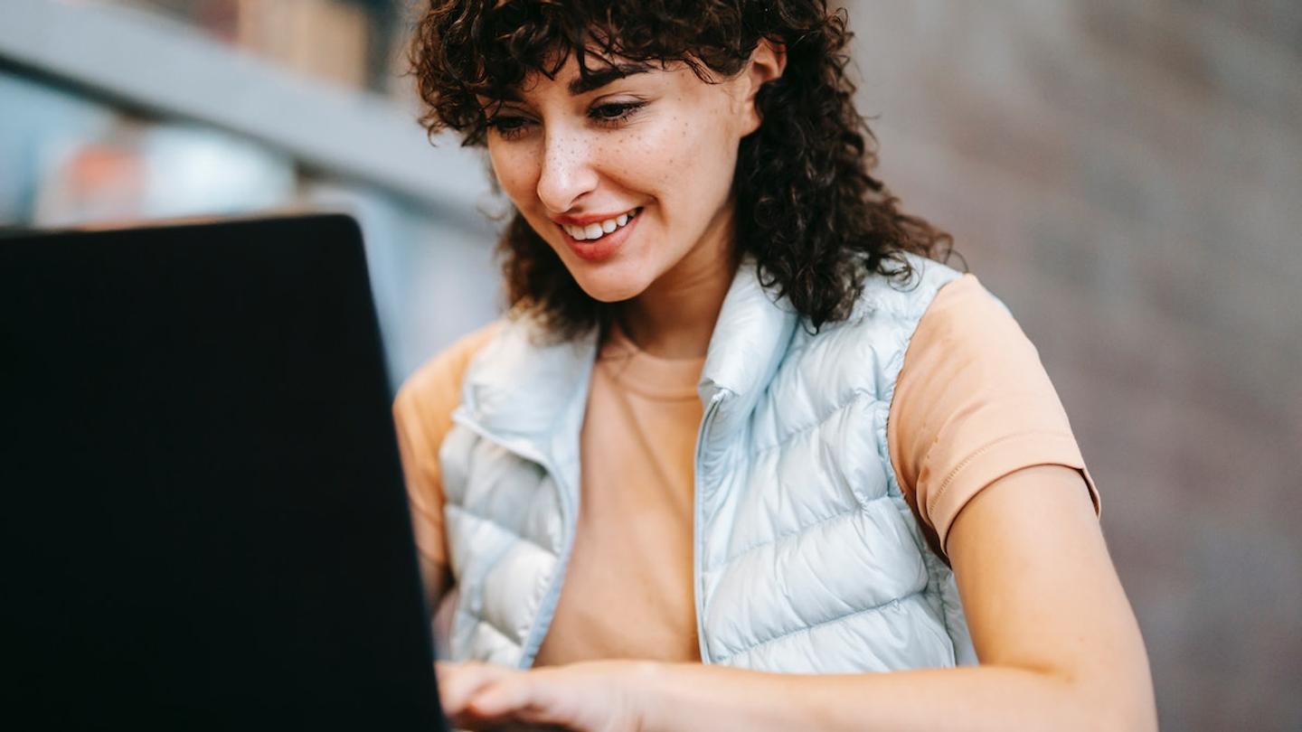A woman setting up a booking system on a black laptop.